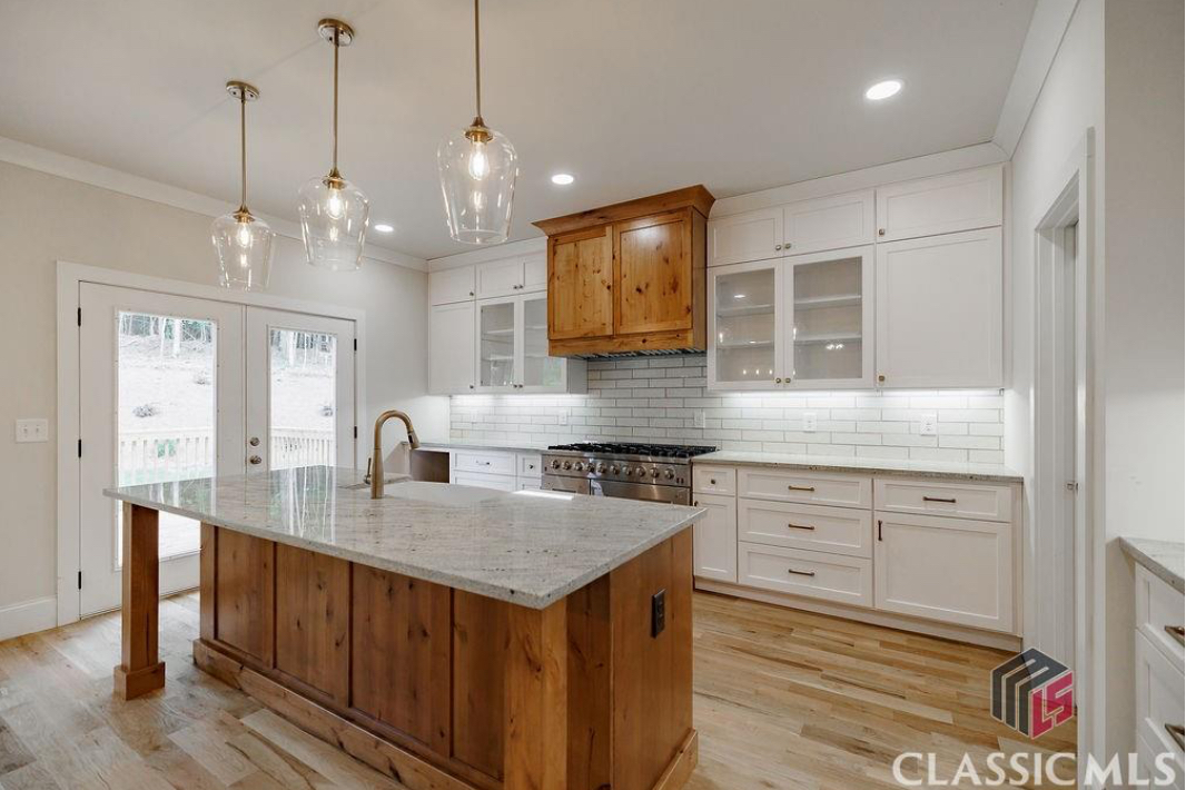 Bright custom white kitchen with a natural wood island by Newberry Cabinets